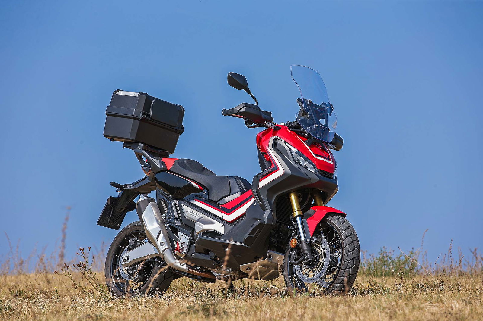 Honda X-ADV color rosso e nero su terreno vista in tre quarti