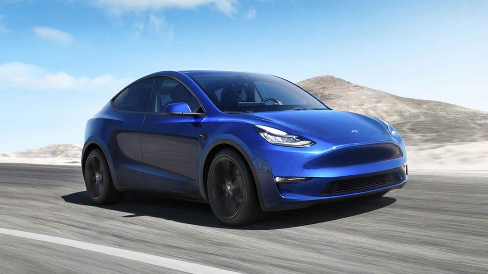 Tesla Model Y auto blu vista tre quarti dinamica su strada sfondo paesaggio