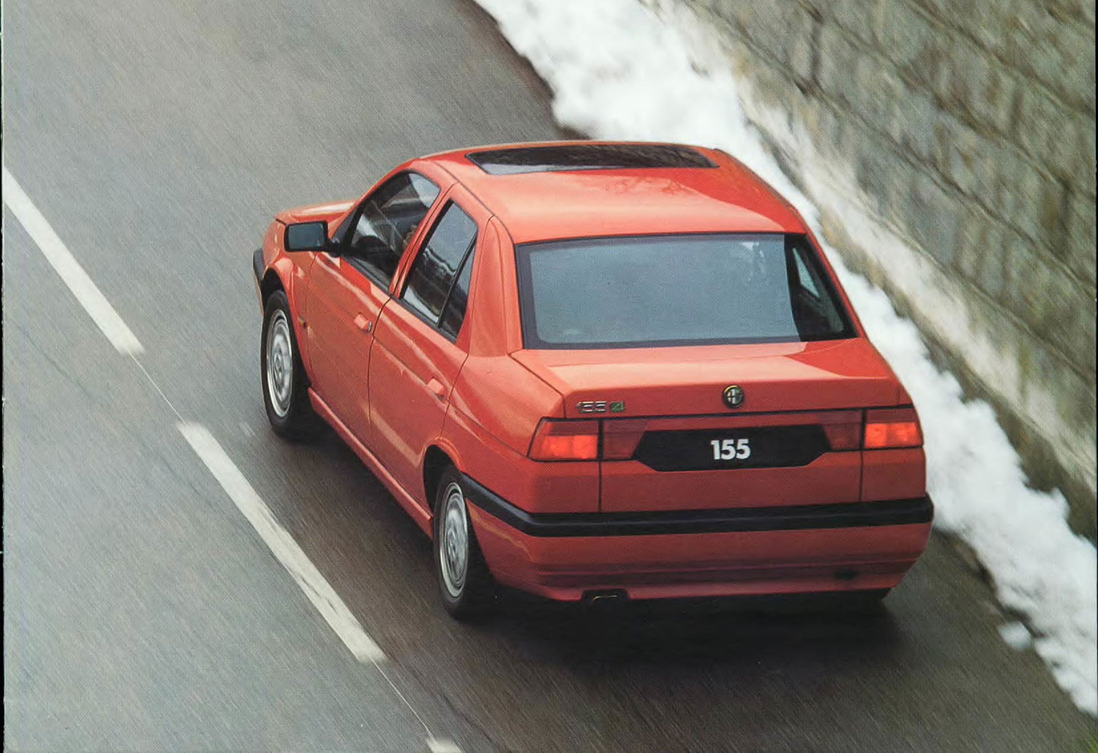 Alfa Romeo 155 Q4 rossa su strada di montagna con neve sui lati