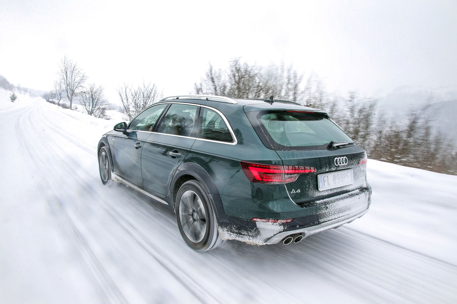 Audi A4 allroad quattro verde vista posteriore dinamica percorre una strada di montagna innevata
