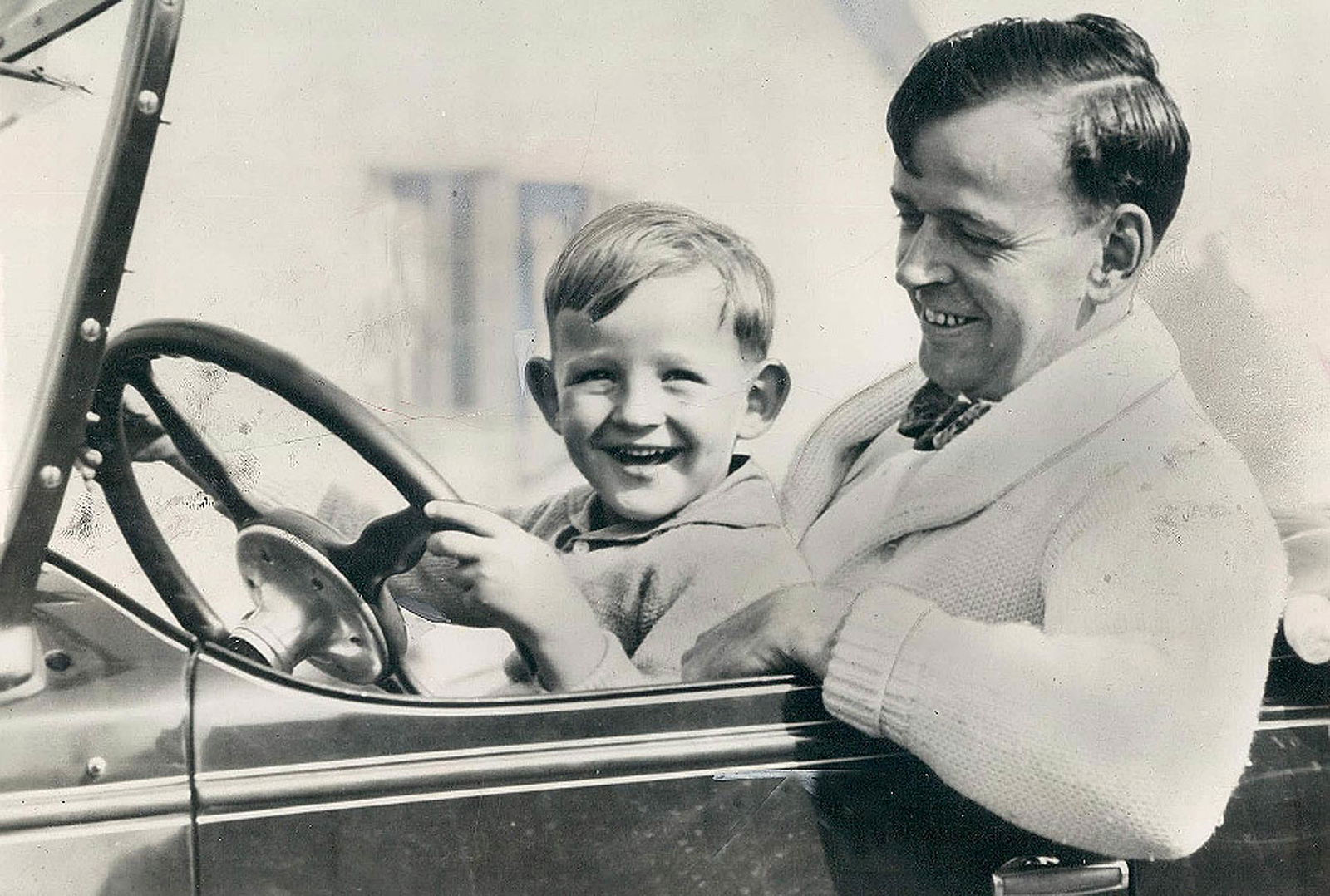 Il papà fa provare al figlio piccolo a guidare l'auto in bianco e nero