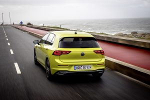 Nuova Volkswagen Golf 8 colo oro su strada con il mare sullo sfondo